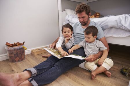 Father Reading Story To Children In Their Bedroomの写真素材