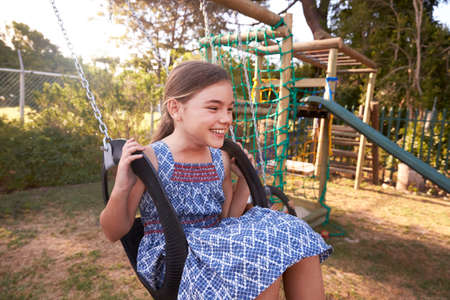 Girl Playing Outdoors At Home On Garden Swing