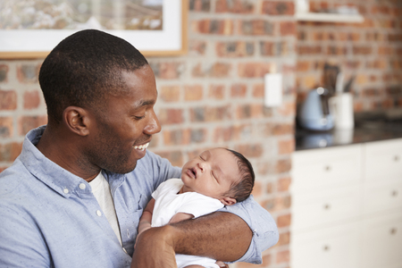 Father At Home Sitting And Holding Newborn Baby Sonの写真素材