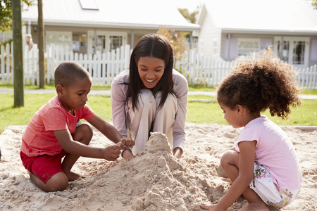 Teacher At Montessori School Playing With Children In Sand Pitの写真素材