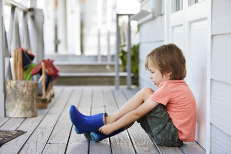 Female Pupil At Montessori School Putting On Wellington Bootsの写真素材