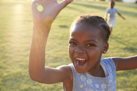 African elementary school girl waving to camera outdoorsの写真素材