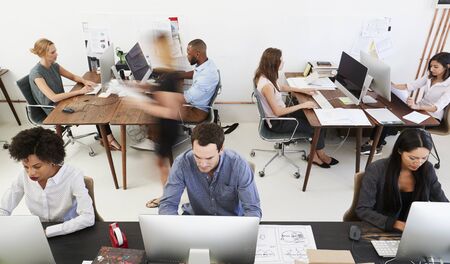 Colleagues at computers in an open plan office, front view