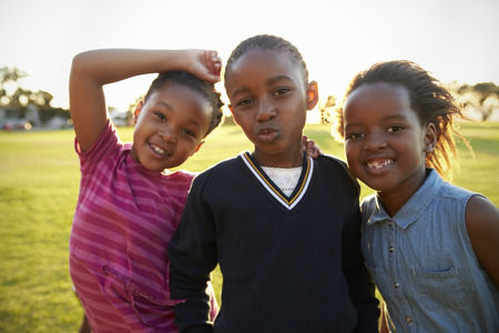 Three African elementary schoolgirls pose to camera in fieldの写真素材