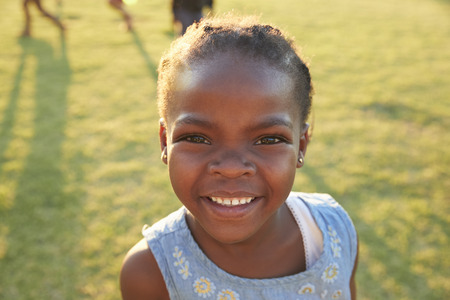 African elementary school girl smiling to camera outdoorsの写真素材