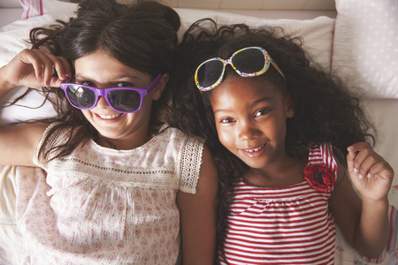 Portrait Of Two Girls Wearing Sunglasses In Bedroom Togetherの写真素材