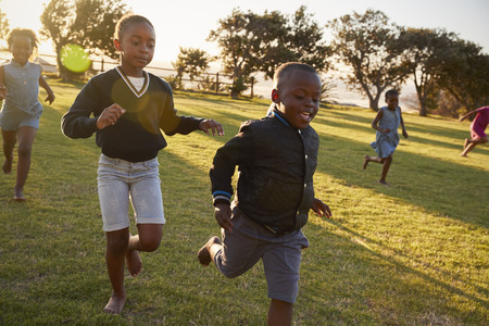 Elementary school kids running to camera in an open fieldの写真素材