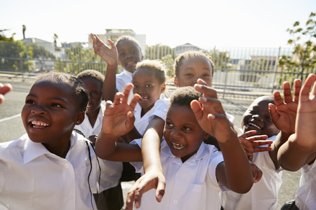 Elementary school kids in playground waving to cameraの写真素材