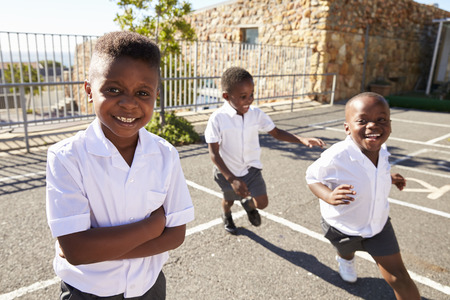 Young African schoolboys running in school playgroundの写真素材