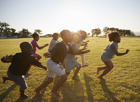 Elementary school kids running together in an open fieldの写真素材