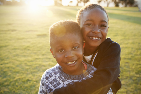 African elementary school boy and girl hugging outdoorsの写真素材