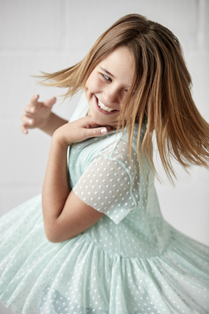 Happy Young Girl Posing In Studio Against White Wallの写真素材