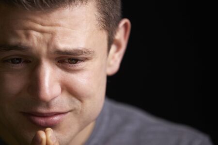Close up of crying young white man looking down, horizontalの写真素材