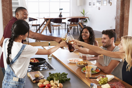 Friends Prepare And Serve Food For Dinner Party At Home Togetherの写真素材