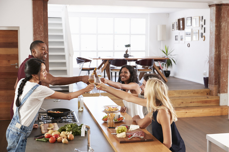 Friends Prepare And Serve Food For Dinner Party At Home Togetherの写真素材