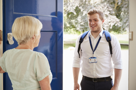 Senior woman greeting male care worker making home visit