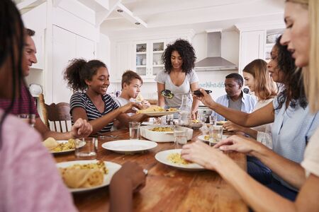 Two Families Enjoying Eating Meal At Home Togetherの写真素材