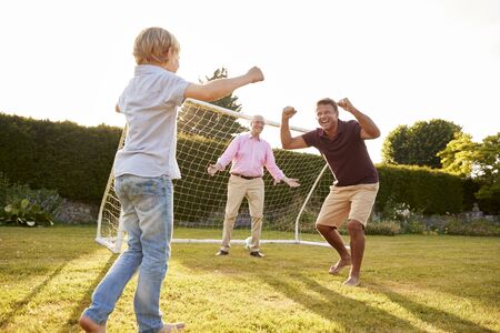 Three male generations of a family cheering in gardenの写真素材