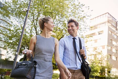 Businessman And Businesswoman Walk to Work Through City Parkの写真素材