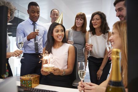 Colleagues gathered at womans desk to celebrate a birthdayの写真素材
