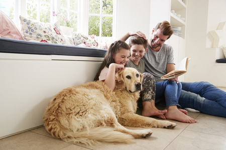 Father Reading Book With Son And Daughter And Pet Dog At Homeの写真素材