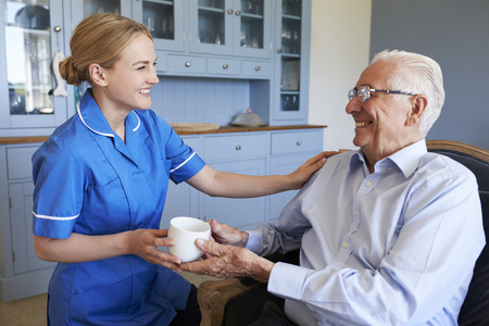 Nurse Giving Senior Man Cup Of Tea On Home Visitの写真素材