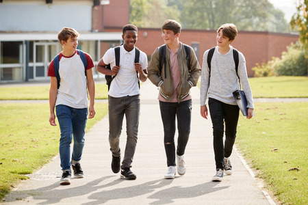 Group Of Male Teenage Students Walking Around College Campusの写真素材