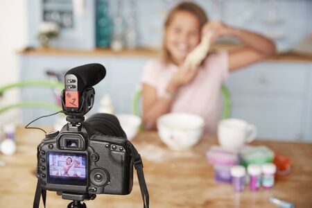Young girl video blogging in kitchen seen through cameraの写真素材