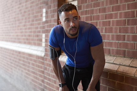 Young man taking a break from running in the streetの写真素材