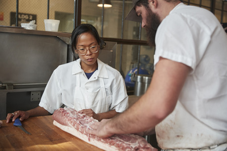 Man and woman preparing meat,cuts of meat to sell at a butcher's shopの写真素材
