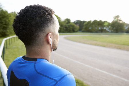 Male athlete at track looking away, close up, back viewの写真素材