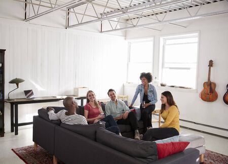 Five young friends socialising in a New York loft apartmentの写真素材