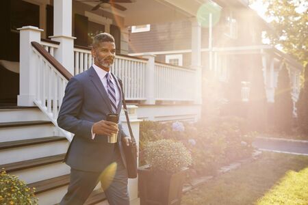 Businessman With Cup Of Coffee Leaving Suburban House For Workの写真素材