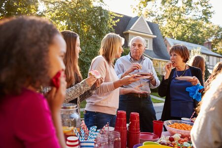 Neighbours talk and eat at a block party, close upの写真素材