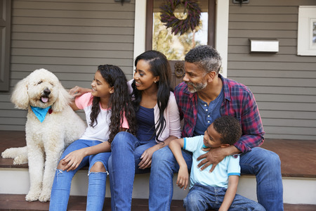 Family With Children And Pet Dog Sit On Steps Of Homeの写真素材