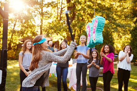 Friends watch teenage girl hitting a picata on her birthday