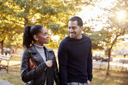 Young Hispanic couple walking hand in hand in Brooklyn parkの写真素材