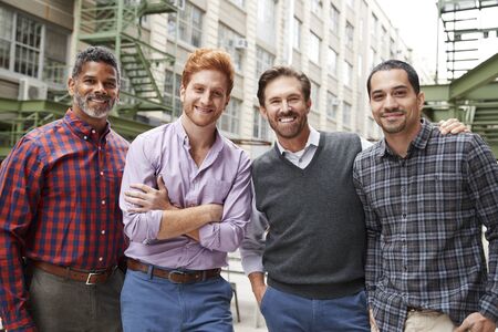 Four male coworkers smiling to camera outsideの写真素材
