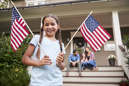 Portrait Of Girl Outside Family Home Holding American Flagsの写真素材