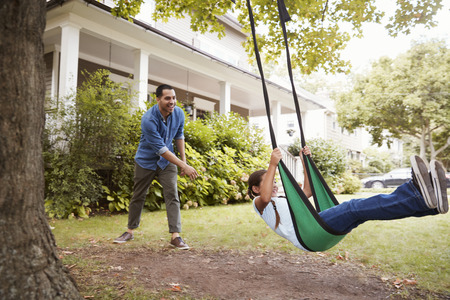 Father Pushing Daughter On Garden Swing At Homeの写真素材