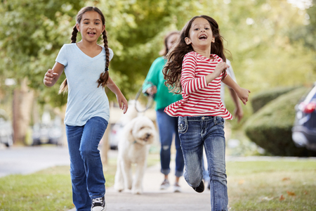 Grandmother And Granddaughters Walking Dog Along Suburban Streetの写真素材
