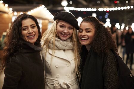 Portrait Of Couple Enjoying Christmas Market At Night