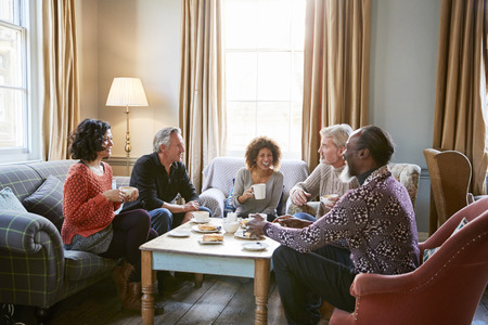 Group Of Middle Aged Friends Meeting Around Table In Coffee Shopの写真素材