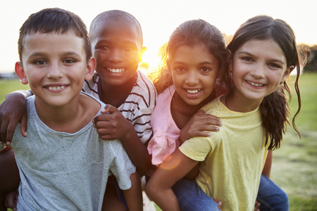 Portrait of smiling young friends piggybacking outdoorsの写真素材