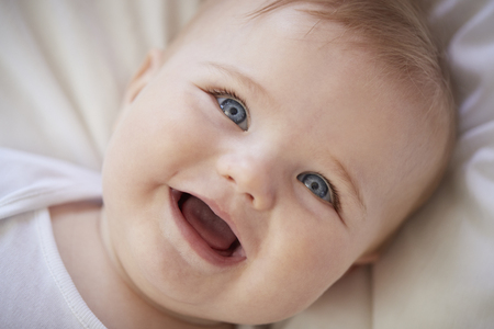 Overhead Shot Of Happy Baby Boy Lying On Parents Bed
