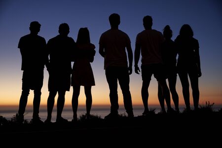 Group of young adults admiring sunset by the sea