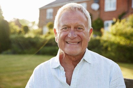 Senior Man Sitting On Garden Bench In Evening Sunlight