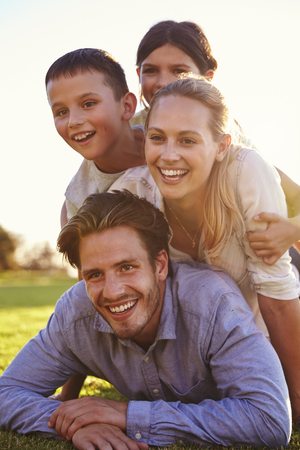 Piled up happy white family lying on grass looking awayの写真素材