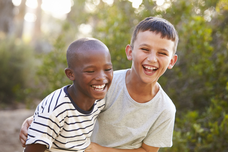 Portrait of two boys embracing and laughing hard outdoorsの写真素材
