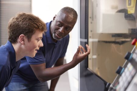 Engineer Showing Apprentice How To Use CNC Tool Making Machineの写真素材
